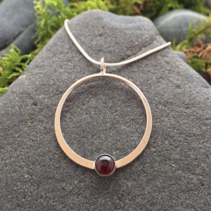 Saucy Jewelry circular pendant with red gemstone